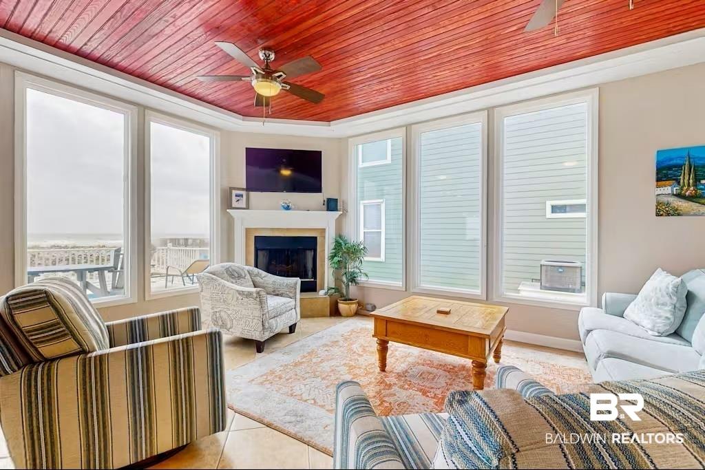 Image 2: Living room with wooden ceiling, a ceiling fan, a fireplace with raised hearth, and light tile patterned flooring