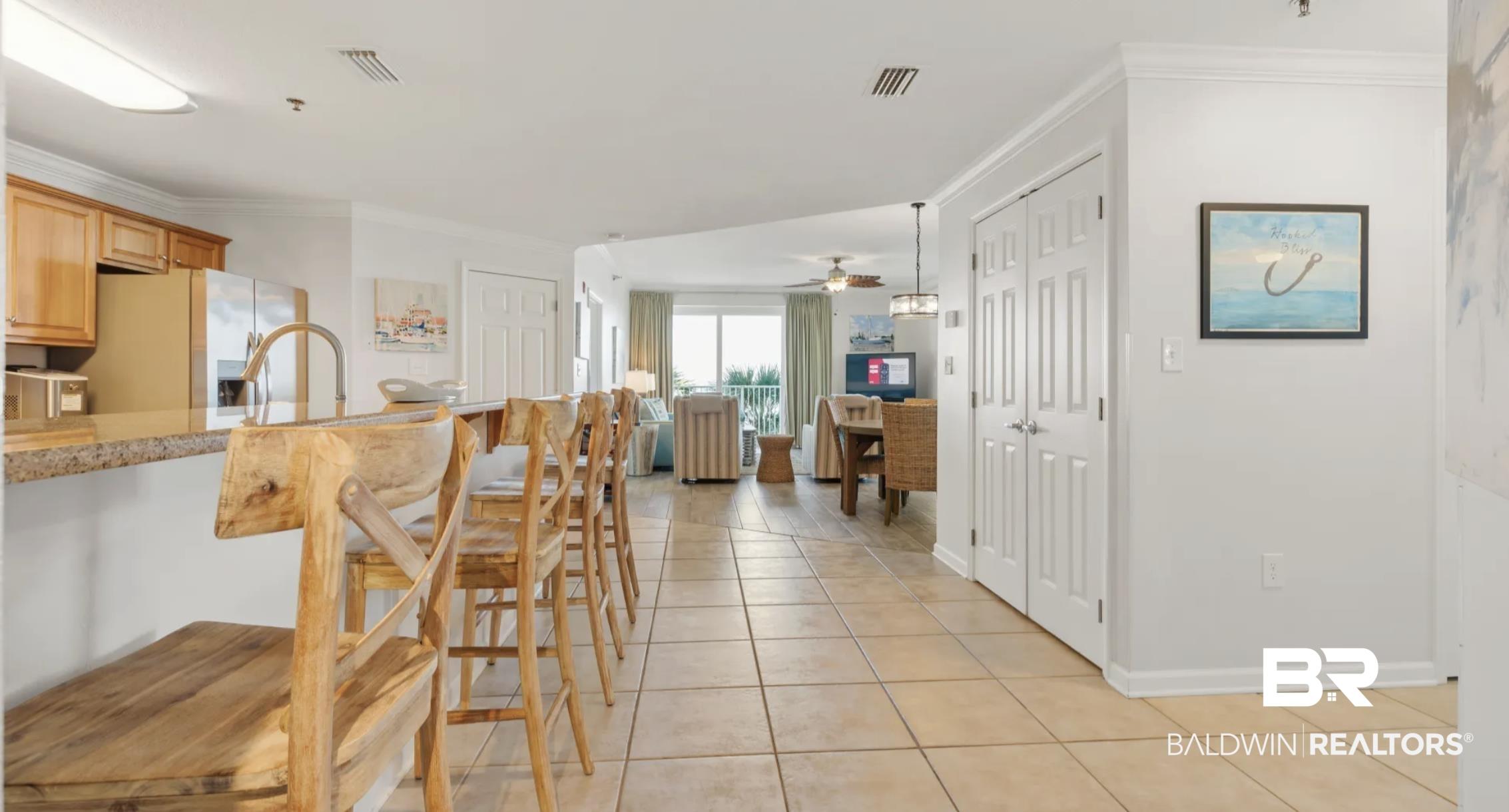 Image 3: Kitchen with a breakfast bar, ornamental molding, stainless steel refrigerator with ice dispenser, light tile patterned floors, and light stone countertops
