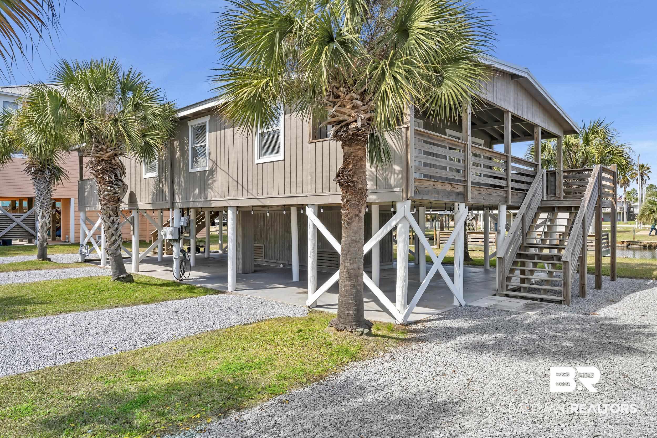 Image 1: Elevated coastal residence featuring a covered front porch, exterior staircase, and ground-level parking
