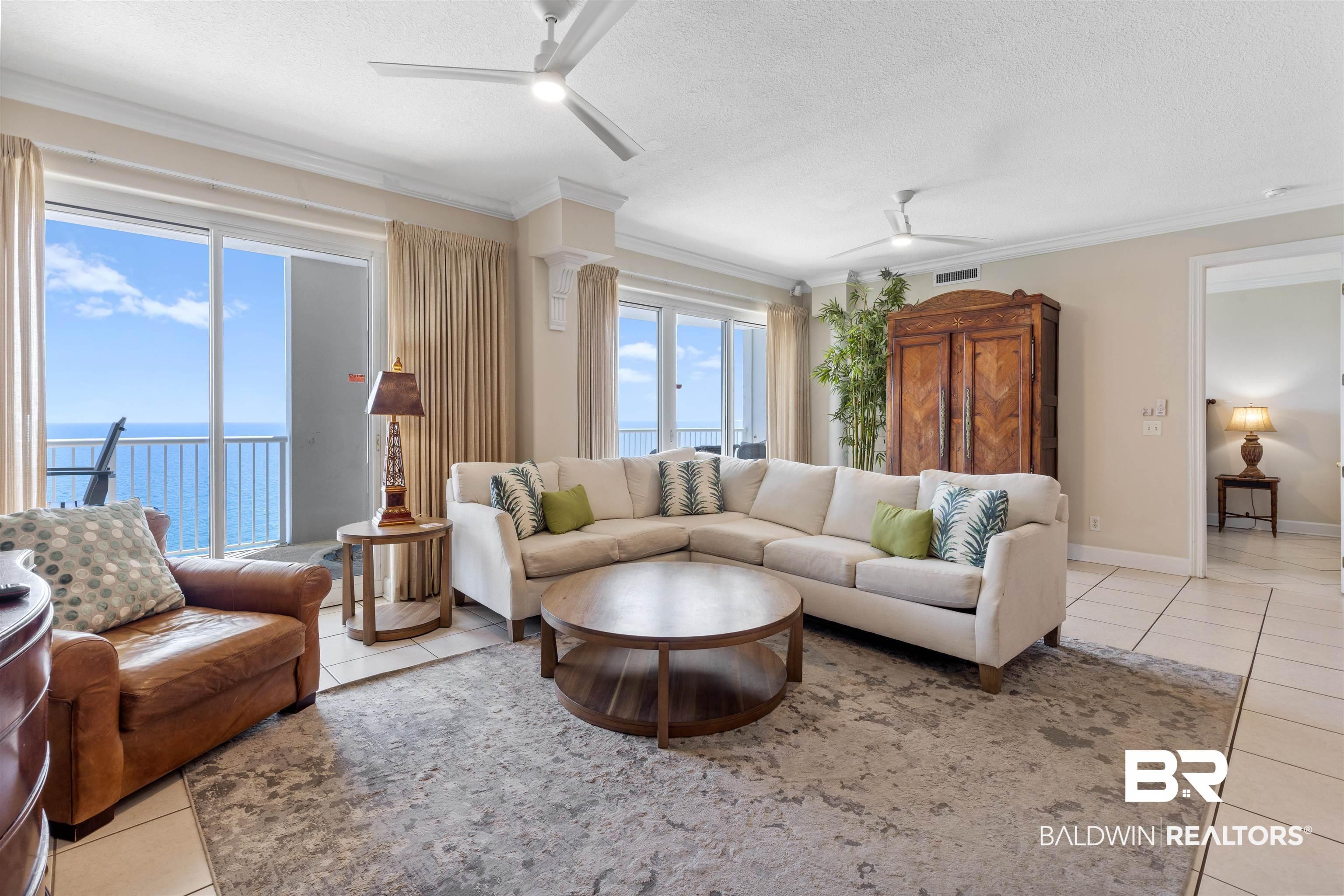 Image 1: Living area featuring light tile patterned floors, a textured ceiling, a water view, a ceiling fan, and ornamental molding