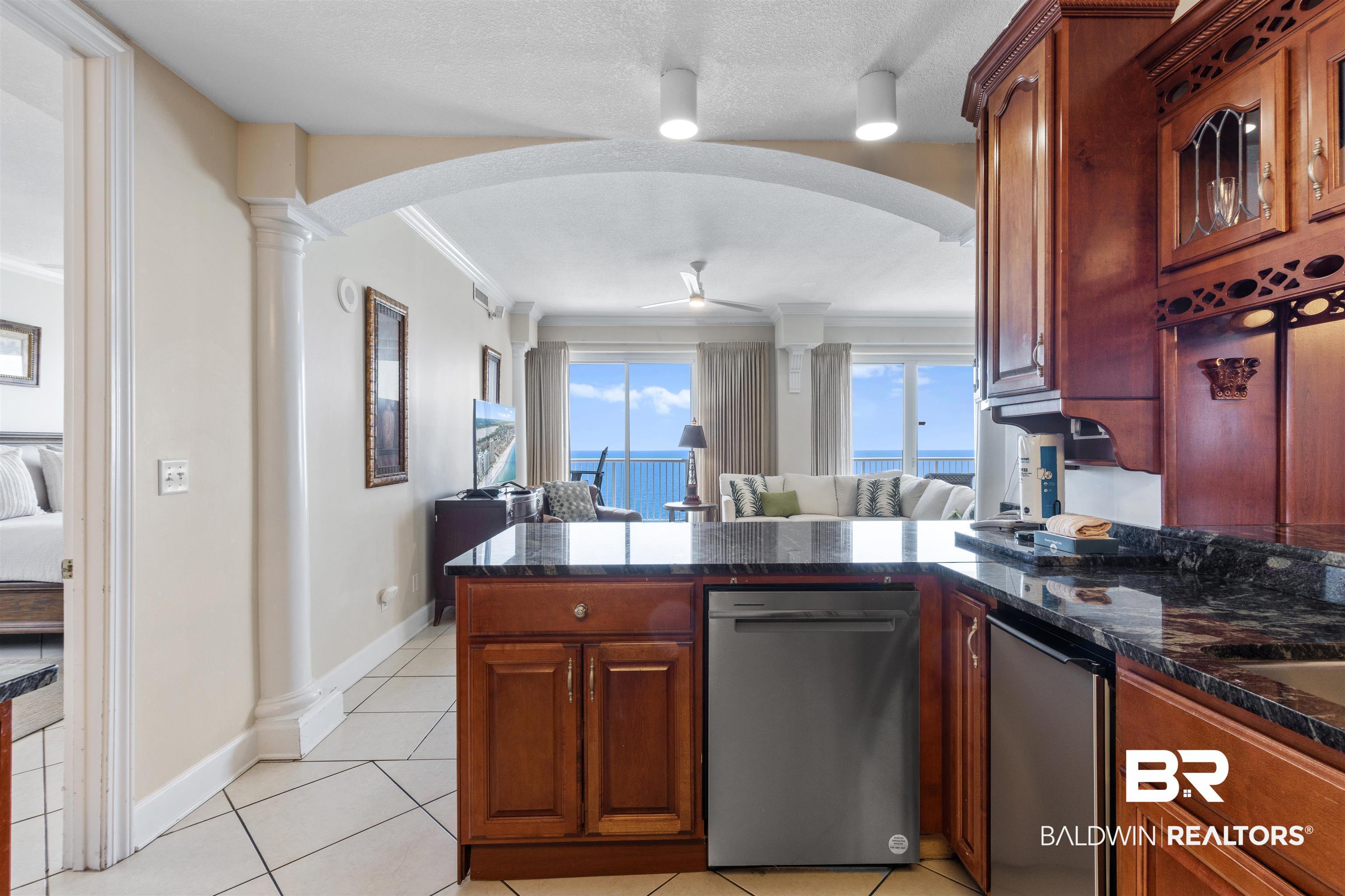 Image 3: Kitchen with open floor plan, stainless steel dishwasher, a peninsula, light tile patterned floors, and a ceiling fan