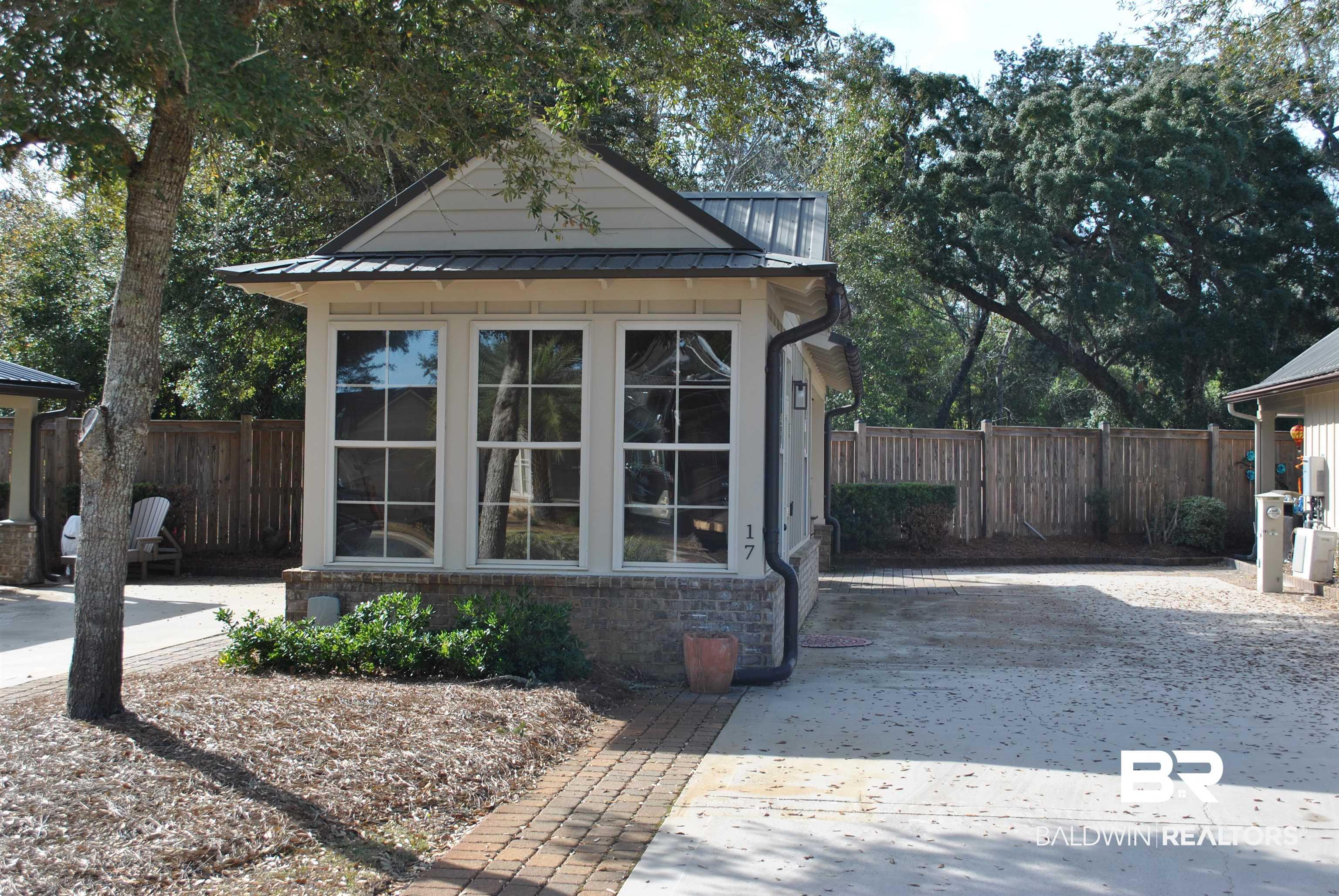 Image 2: View of front of property featuring a standing seam roof, a fenced backyard, brick siding, and a patio