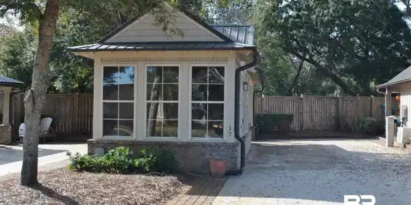 Image 2: View of front of property featuring a standing seam roof, a fenced backyard, brick siding, and a patio