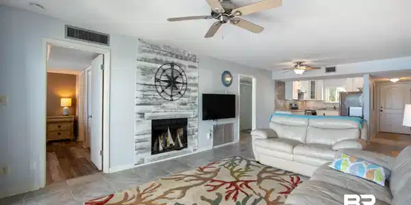 Image 4: Living area featuring a white-washed plank accent wall, a built-in fireplace, and tile flooring