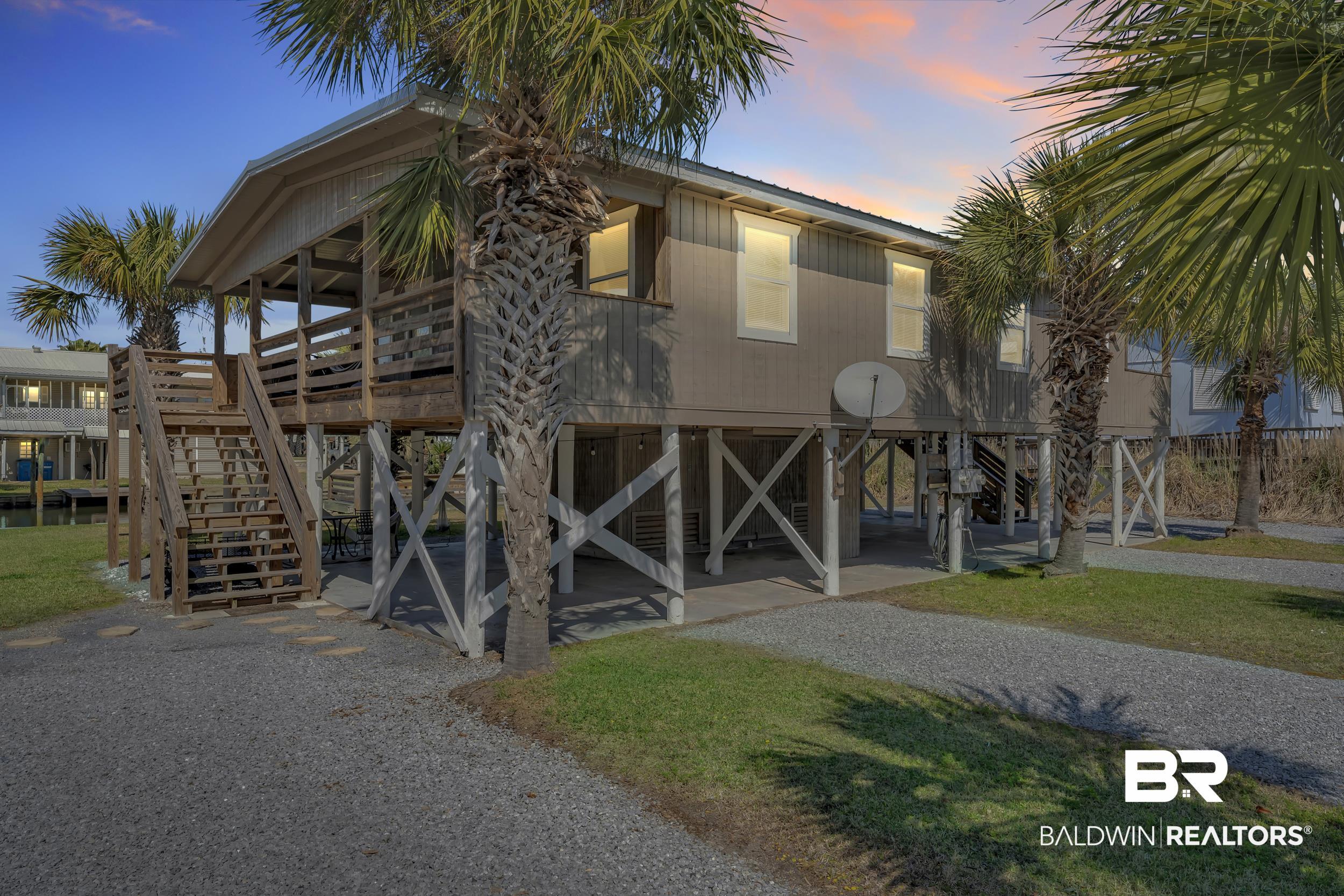 Image 3: Elevated coastal-style residence featuring a spacious covered deck and exposed pilings