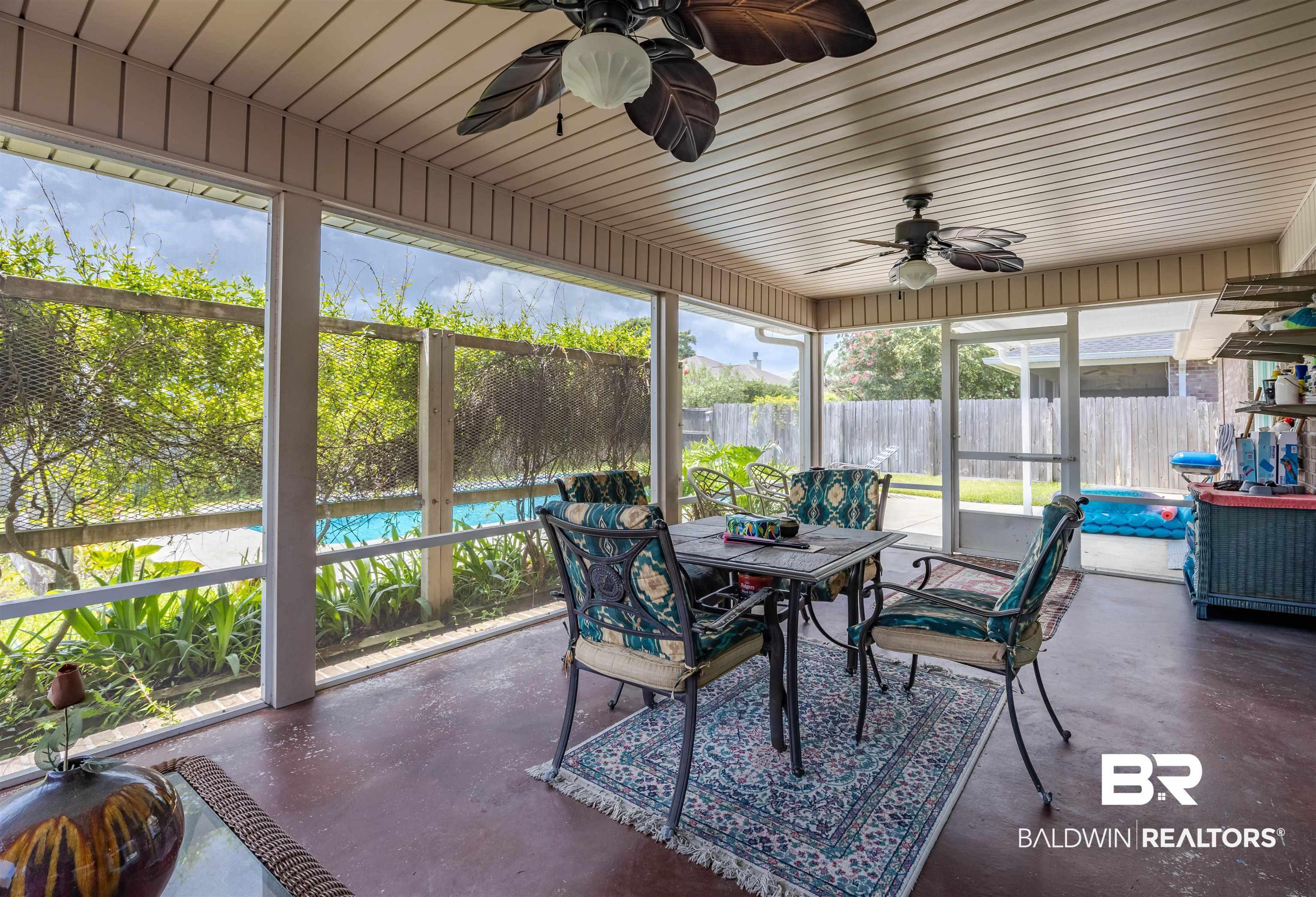 Image 2: Screened patio featuring a solid ceiling with two ceiling fans, direct access to the backyard, and a clear view of the pool