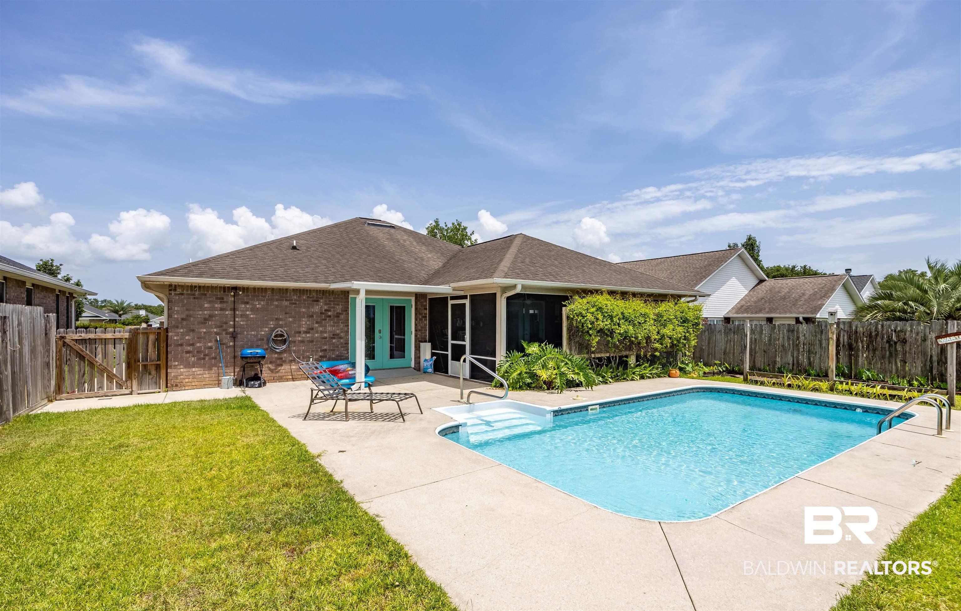 Image 3: Expansive backyard featuring a rectangular in-ground swimming pool with concrete decking, a privacy fence, and mature landscaping