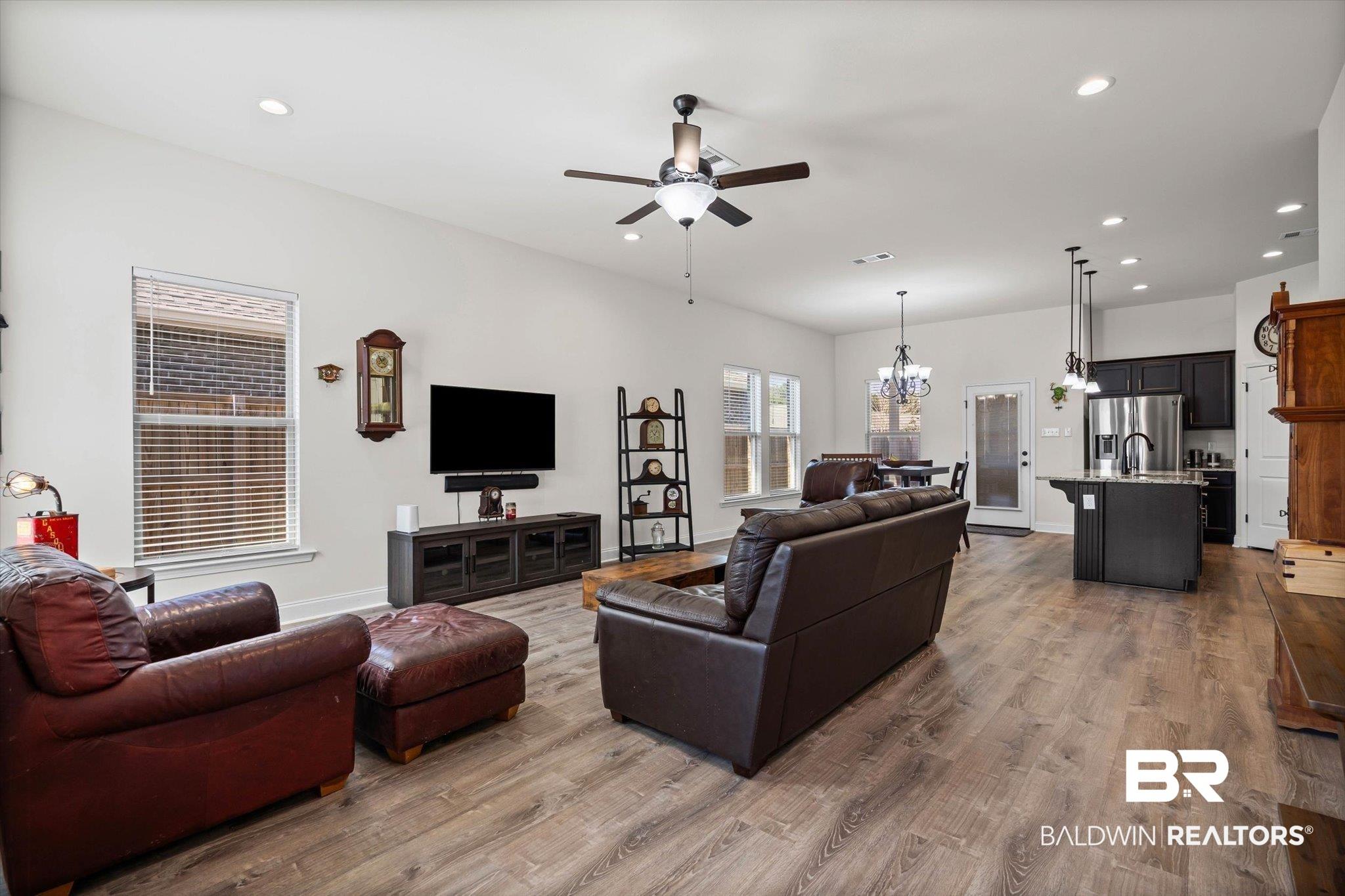 Image 2: Living room featuring suspended lighting, a ceiling fan, and wood finished floors