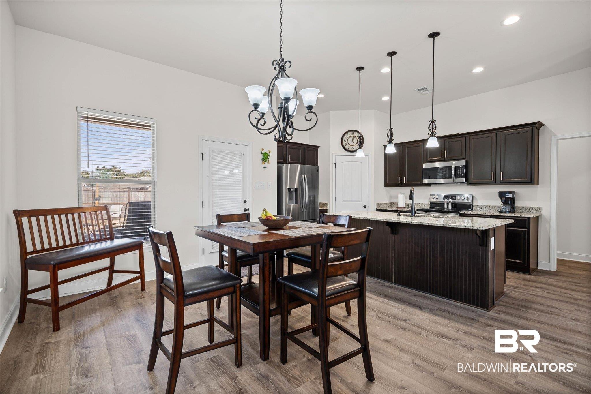 Image 3: Dining area with hanging lights and light wood-style flooring