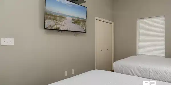 Image 3: Wall-mounted television and window with horizontal blinds