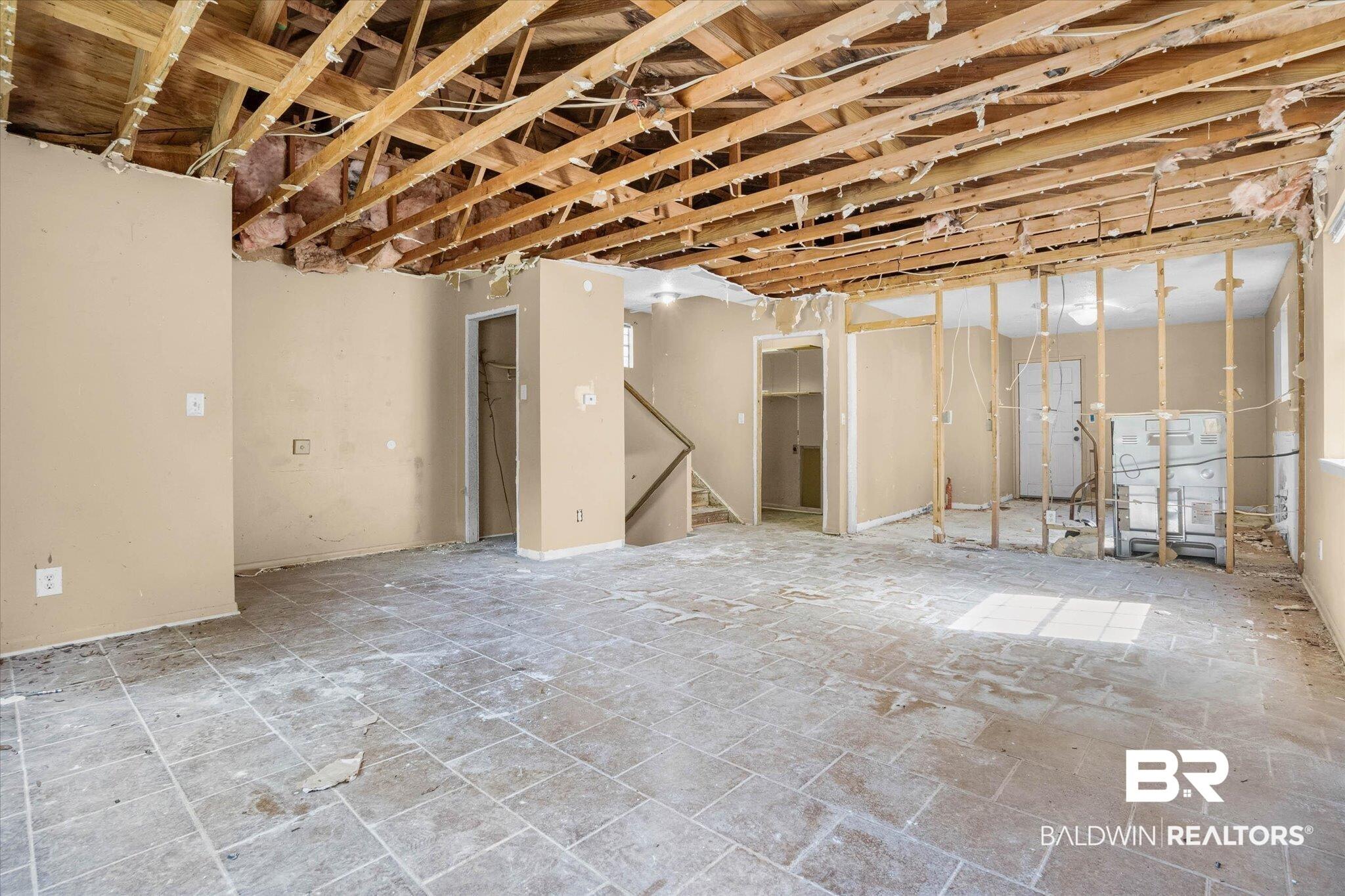 Image 3: Interior space featuring exposed ceiling joists and wall studs, partial drywall, and tiled flooring