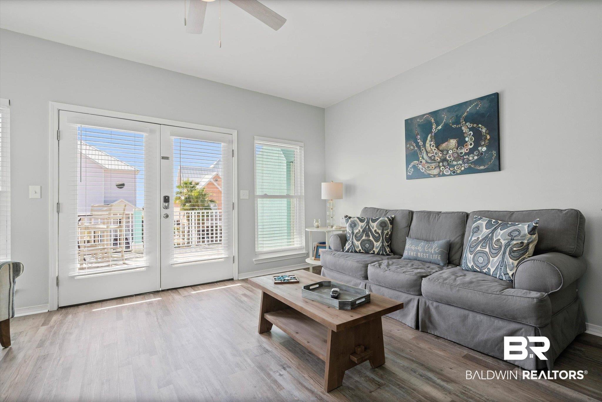 Image 4: Living room with LVP  wood  floors and french doors leading to deck