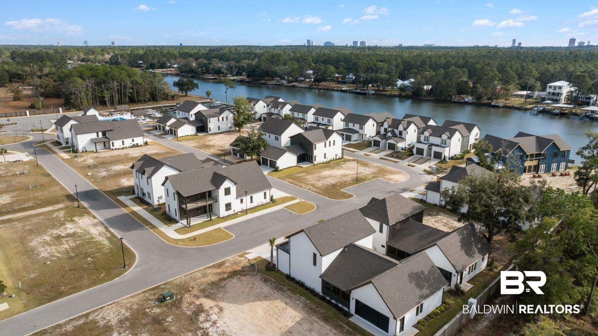 Image 4: Aerial perspective of suburban area featuring a large body of water and a tree filled landscape