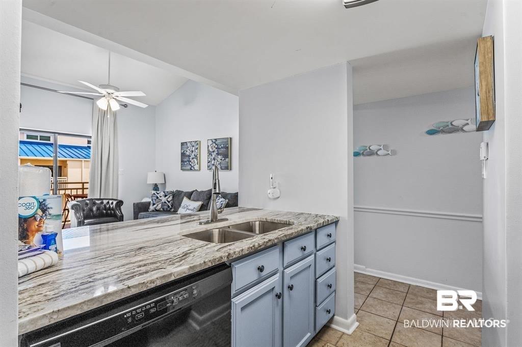 Image 2: Kitchen with light stone counters, black dishwasher, ceiling fan, lofted ceiling, and light tile patterned floors