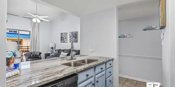 Image 2: Kitchen with light stone counters, black dishwasher, ceiling fan, lofted ceiling, and light tile patterned floors