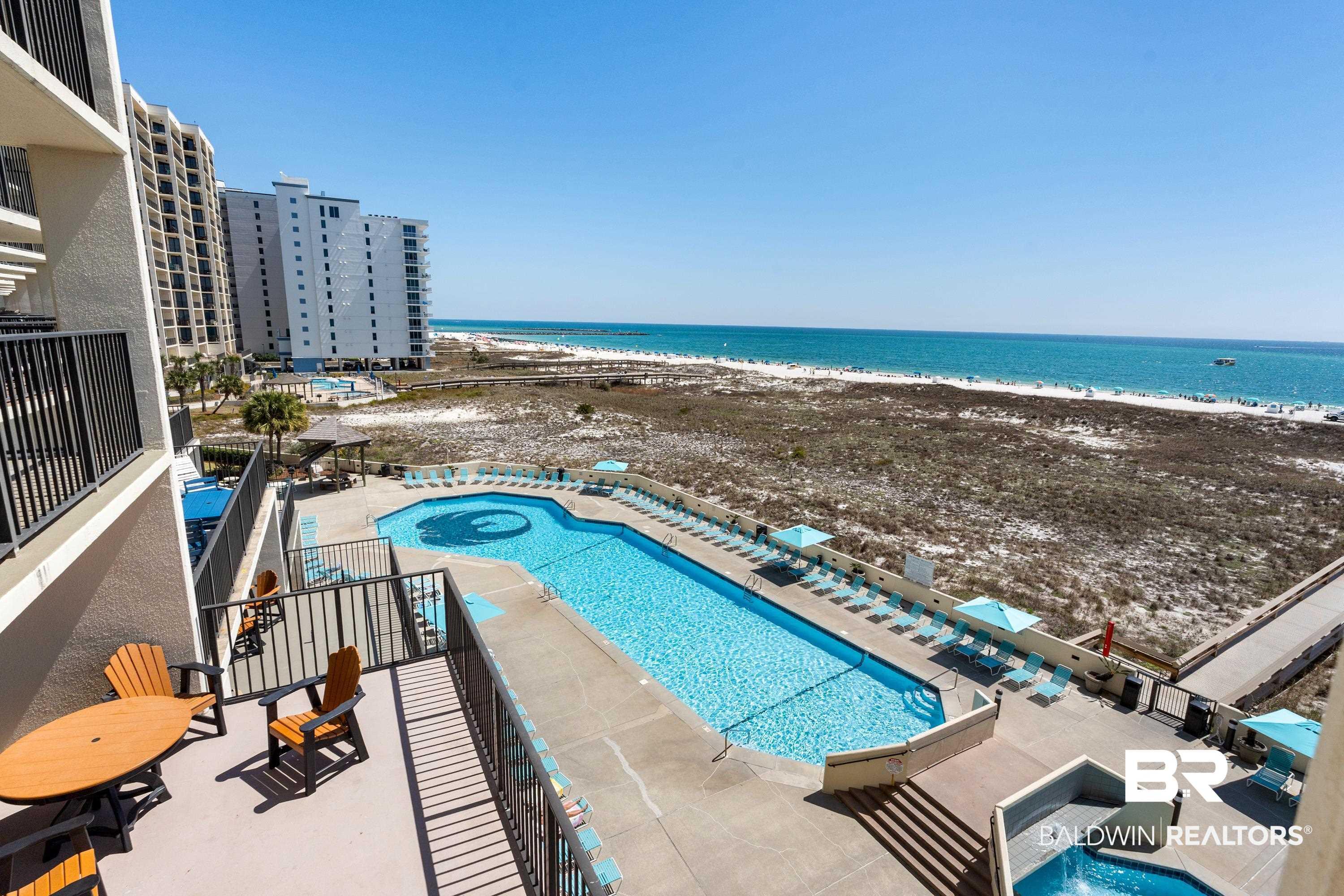 Image 2: Community pool with a jacuzzi, a patio area, view of water and beach, and a balcony