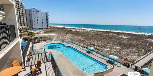 Image 2: Community pool with a jacuzzi, a patio area, view of water and beach, and a balcony
