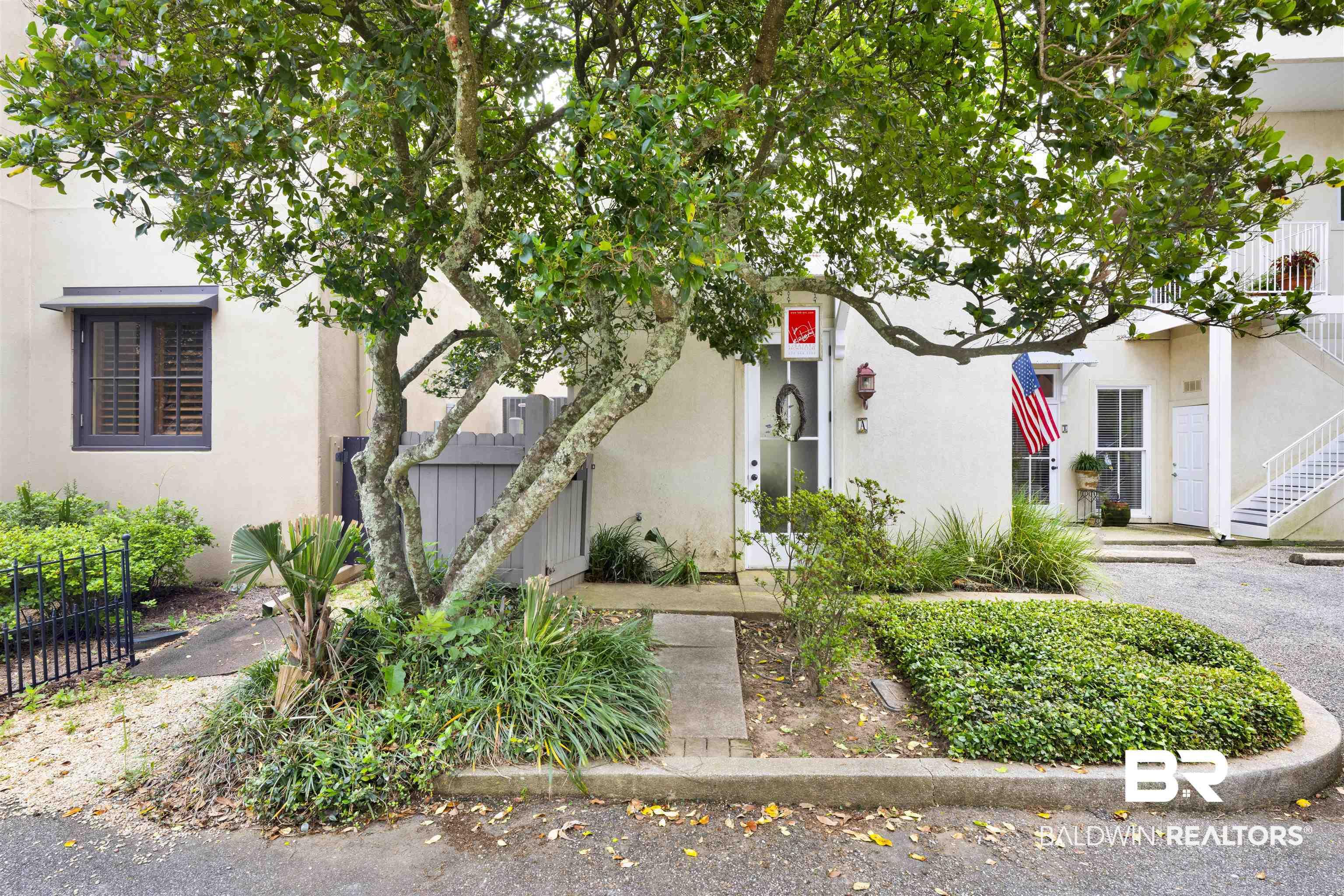 Image 3: Exterior facade featuring stucco finish, a prominent mature tree, and diverse landscaping