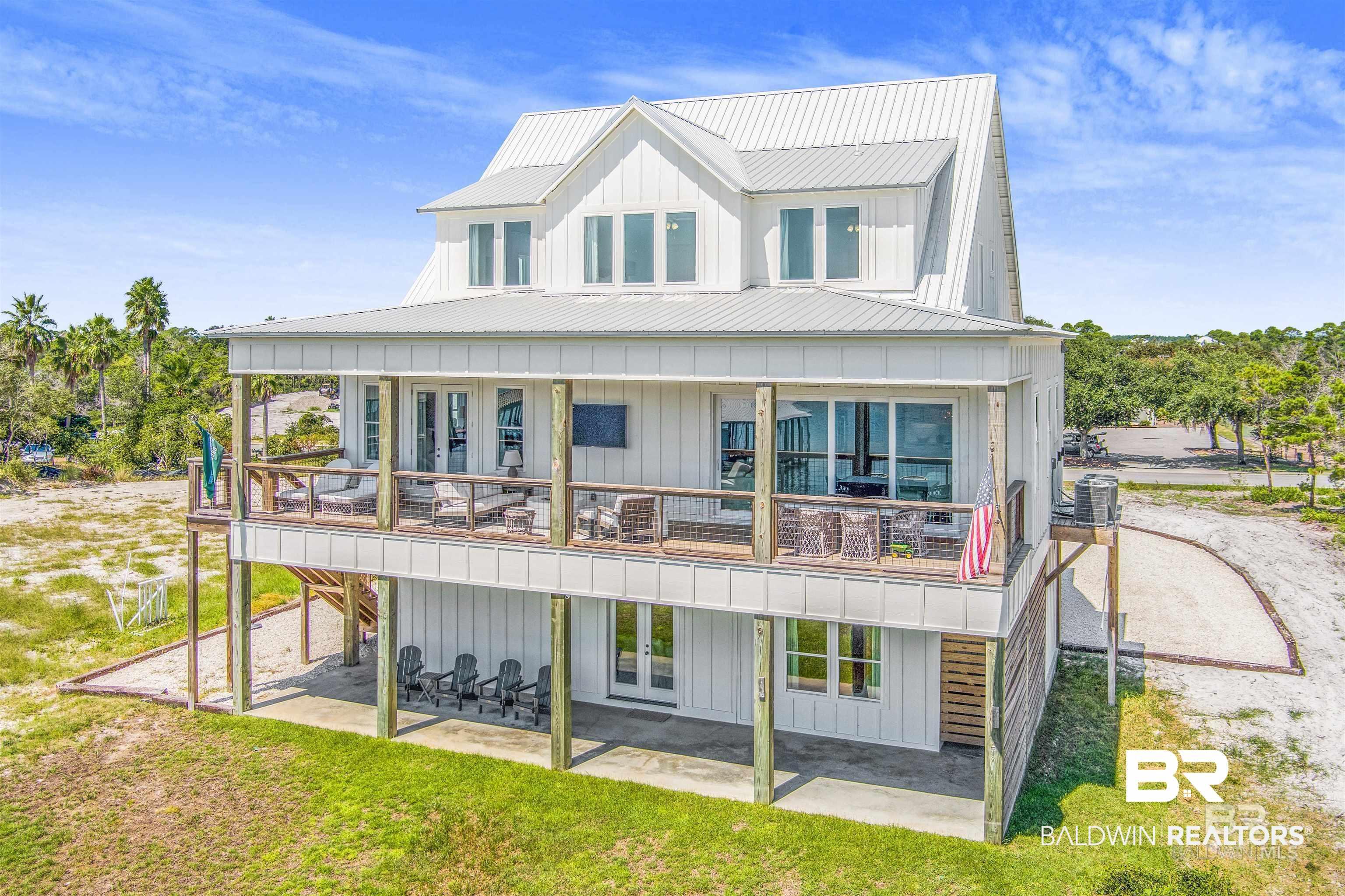 Image 2: Three-story residence featuring white board and batten siding and a metal roof