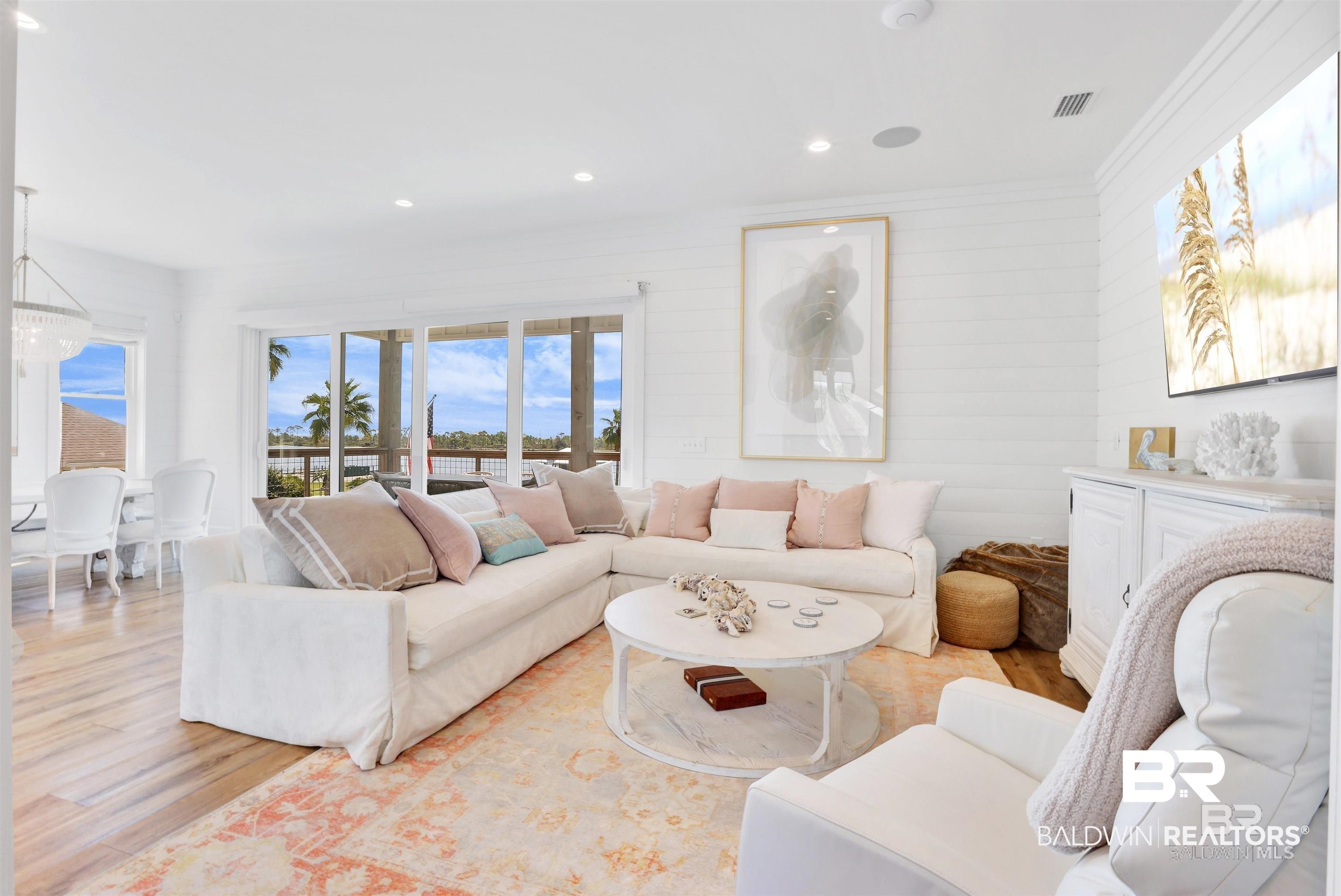 Image 4: Living area with wood-finish flooring, shiplap accent wall, recessed lighting, and expansive sliding glass doors
