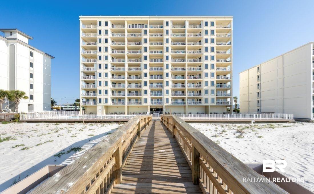 Image 1: Multi-story residential building with private balconies and a direct boardwalk entry point to the sandy area