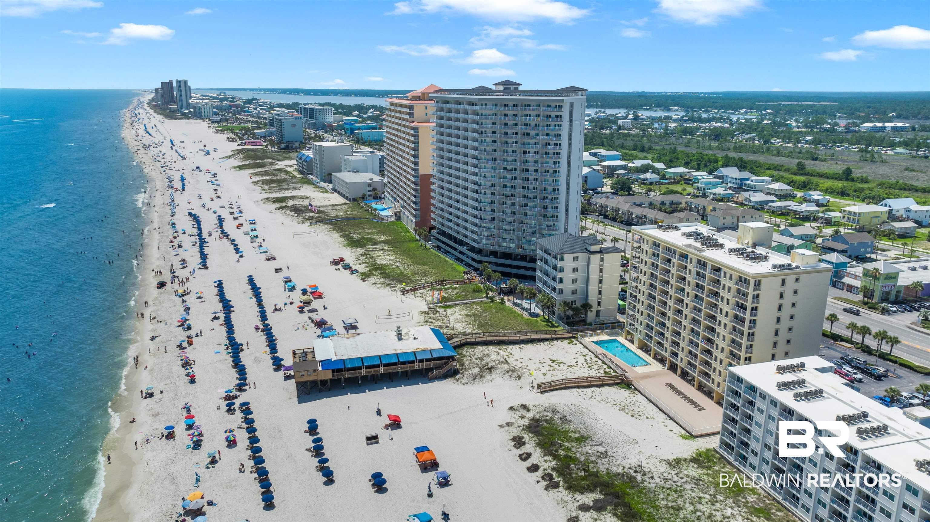 Image 4: Coastal high-rise property featuring direct beach access, an outdoor swimming pool, and dedicated parking