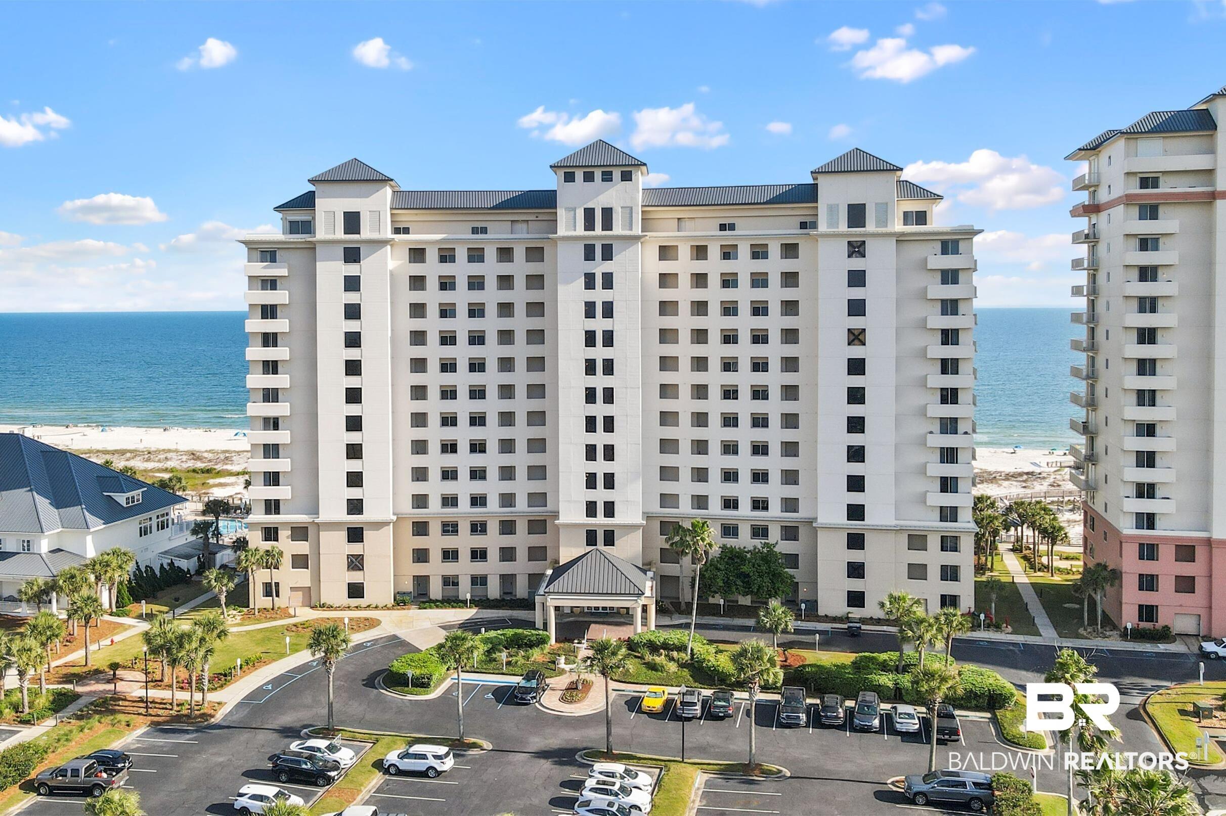 Image 2: View of apartment building / complex with view of water and beach and uncovered parking