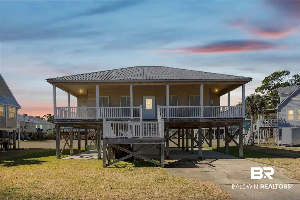 Image 1: Beach home with a carport, a front yard, a metal roof, covered porch, and driveway
