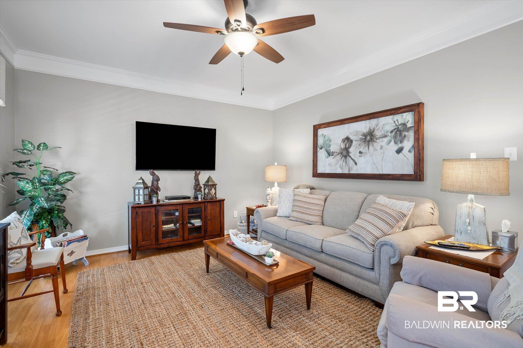 Image 3: Living area featuring ceiling fan, wood finished floors, and ornamental molding