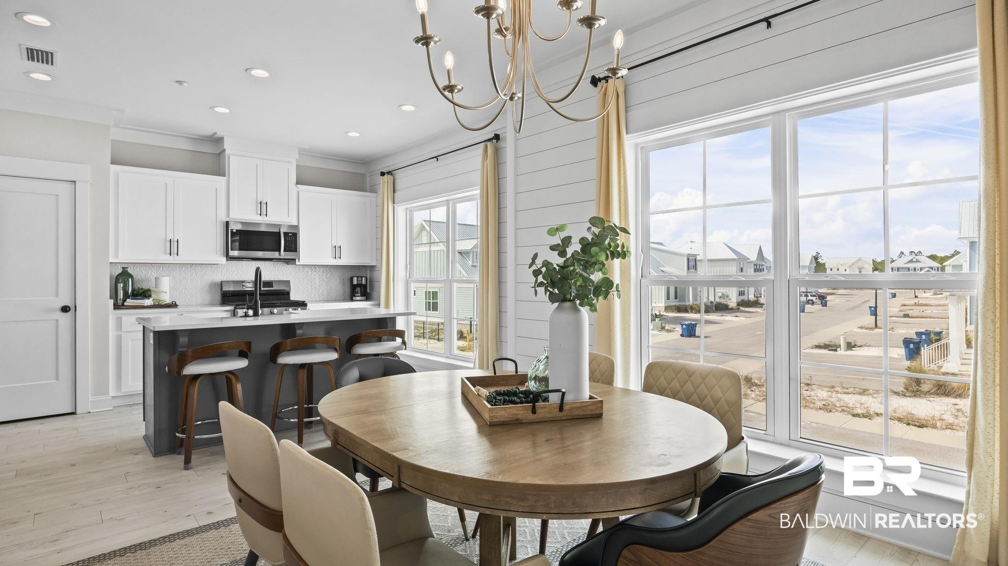 Image 4: Dining area with ornamental molding, light wood-style floors, and a chandelier
