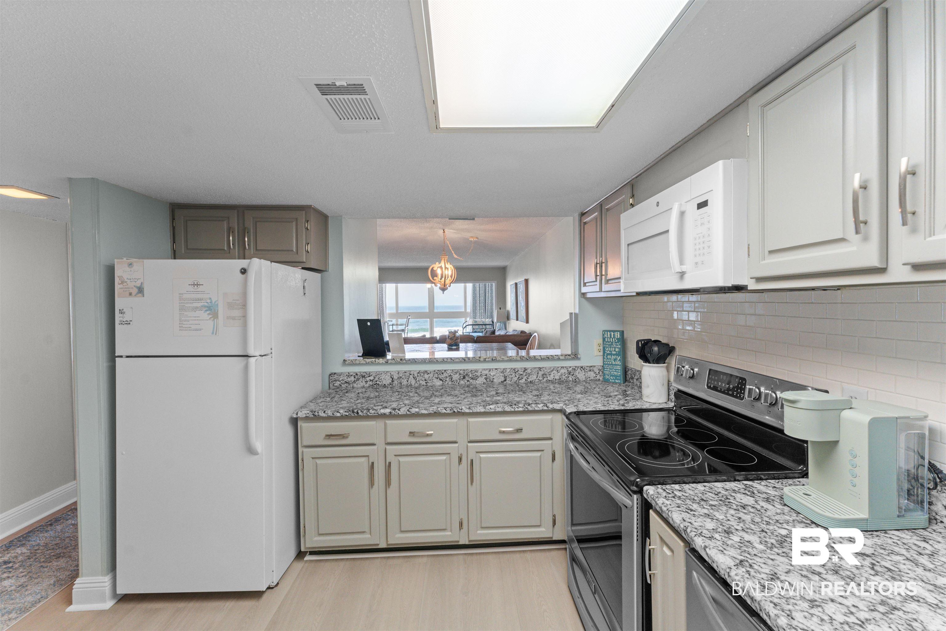 Image 4: Kitchen featuring granite-look countertops, white cabinetry, and a subway tile backsplash