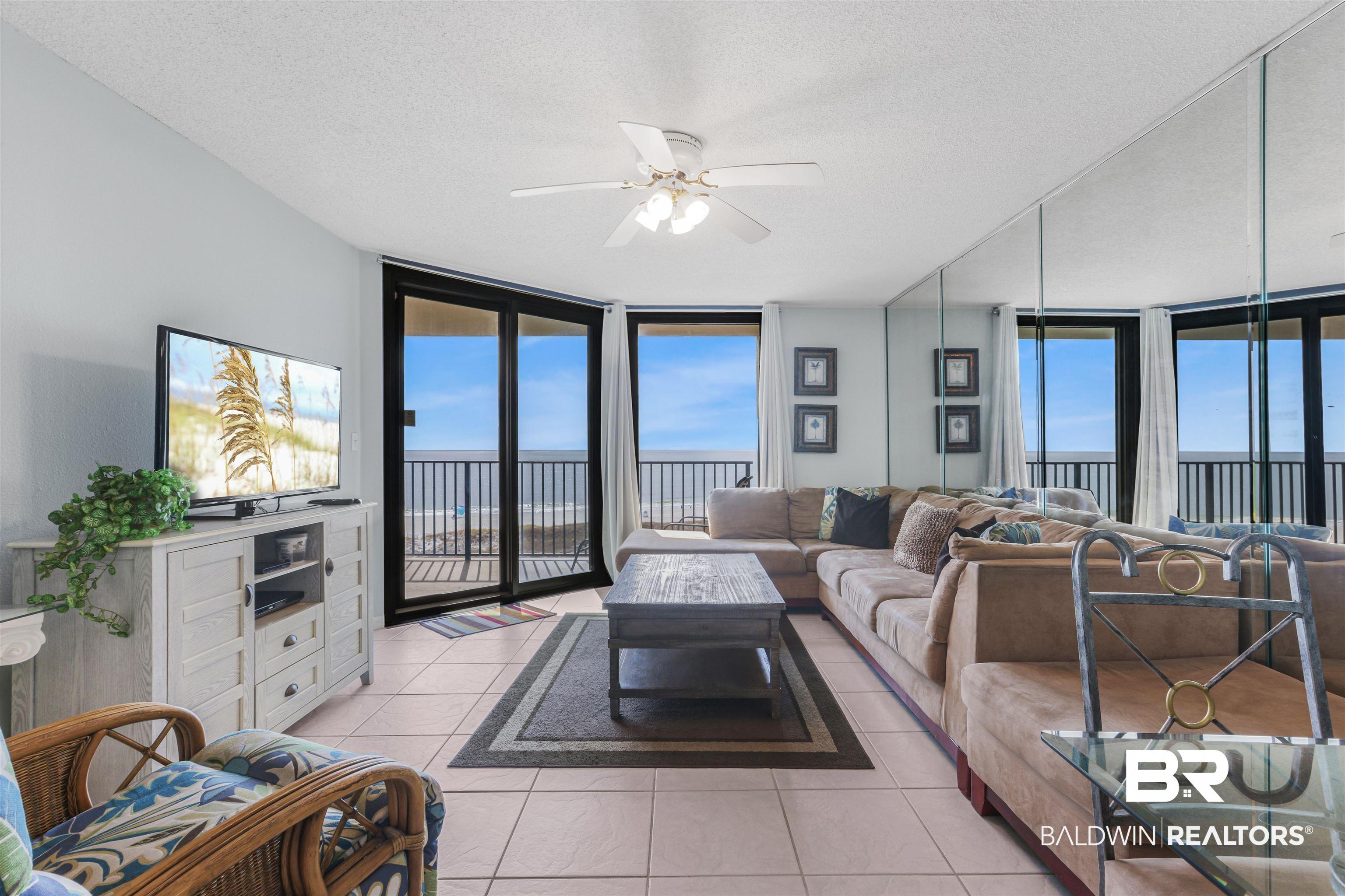 Image 4: Living room with a wall of windows, light tile patterned floors, a textured ceiling, and a ceiling fan