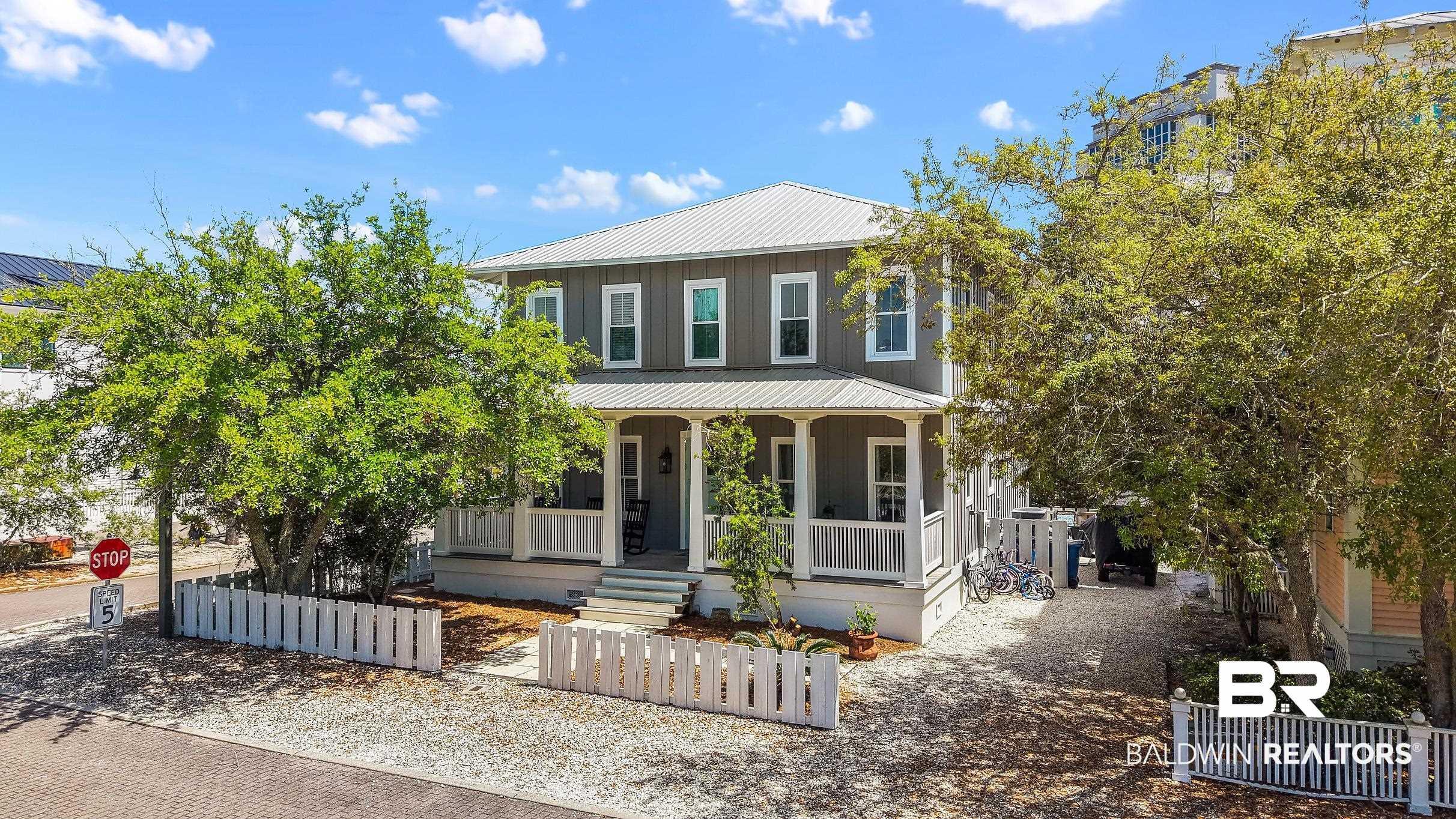 Image 4: Two-story residence featuring a gray exterior with white trim, a metal roof, and a covered front porch with white railings
