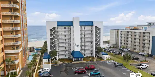 Image 2: Multi-story building featuring a white facade and blue roofing accents