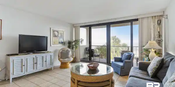 Image 3: Living area featuring tile flooring, white walls, and a built-in media console with louvered doors