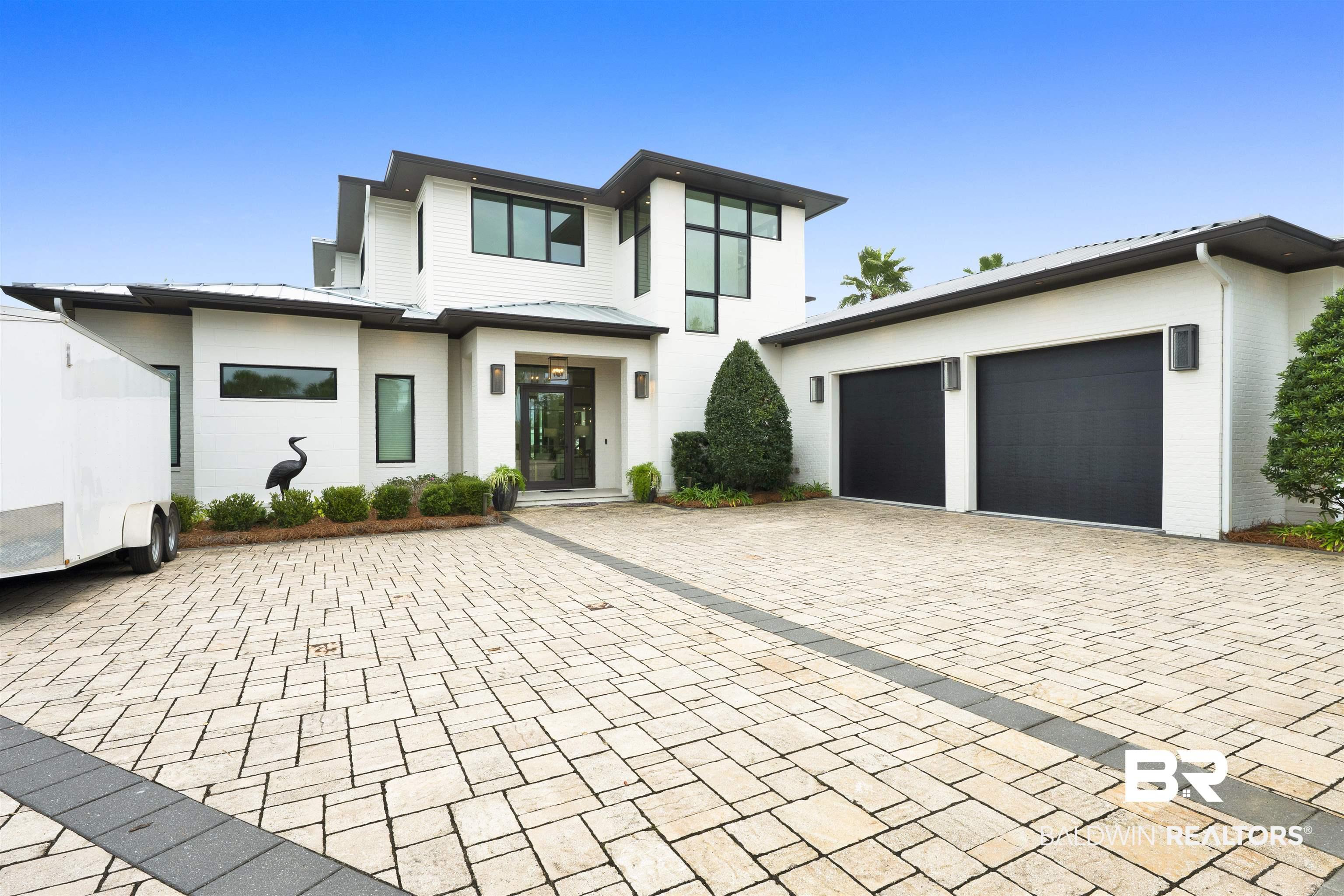 Image 2: View of front of property featuring a metal roof, a garage, decorative driveway, and brick siding