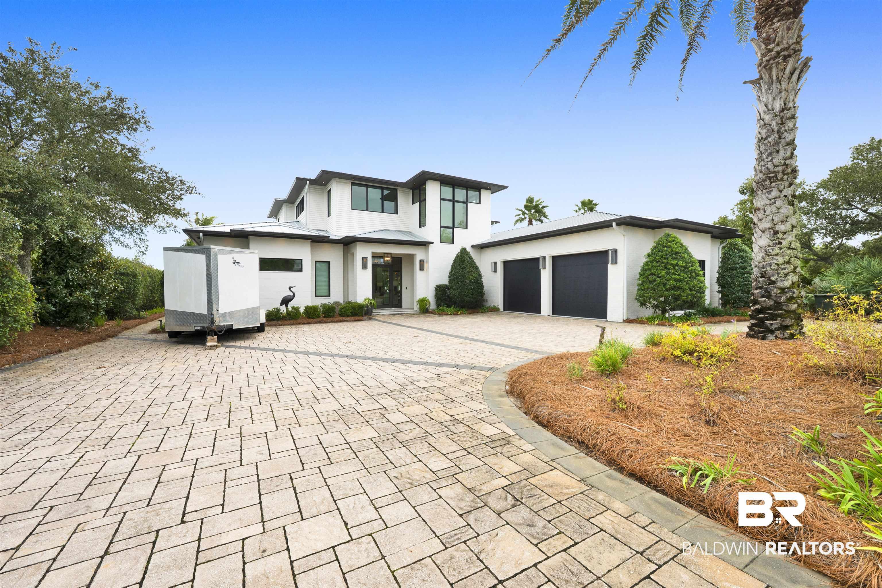 Image 3: View of front facade with stucco siding and decorative driveway