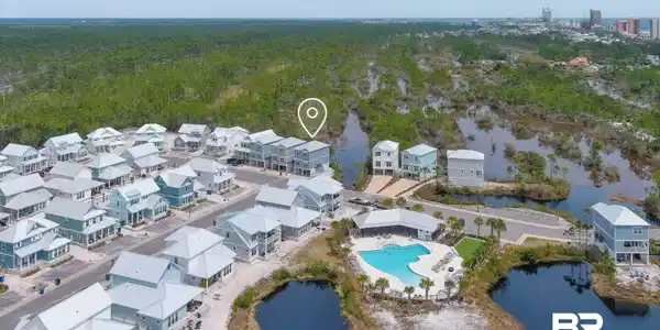 Image 2: Aerial perspective of a structured residential community featuring a central resort-style pool with surrounding lounge areas, mature palm trees, and clear water features