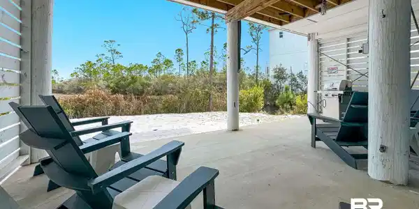 Image 3: Covered outdoor patio area featuring a concrete slab foundation, exposed wood beam ceiling, and white slatted wall details