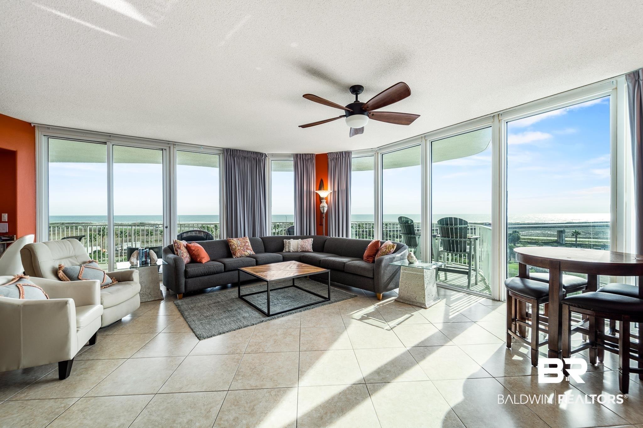 Image 2: Living area with expansive windows, a textured ceiling, ceiling fan, a water view, and light tile patterned floors
