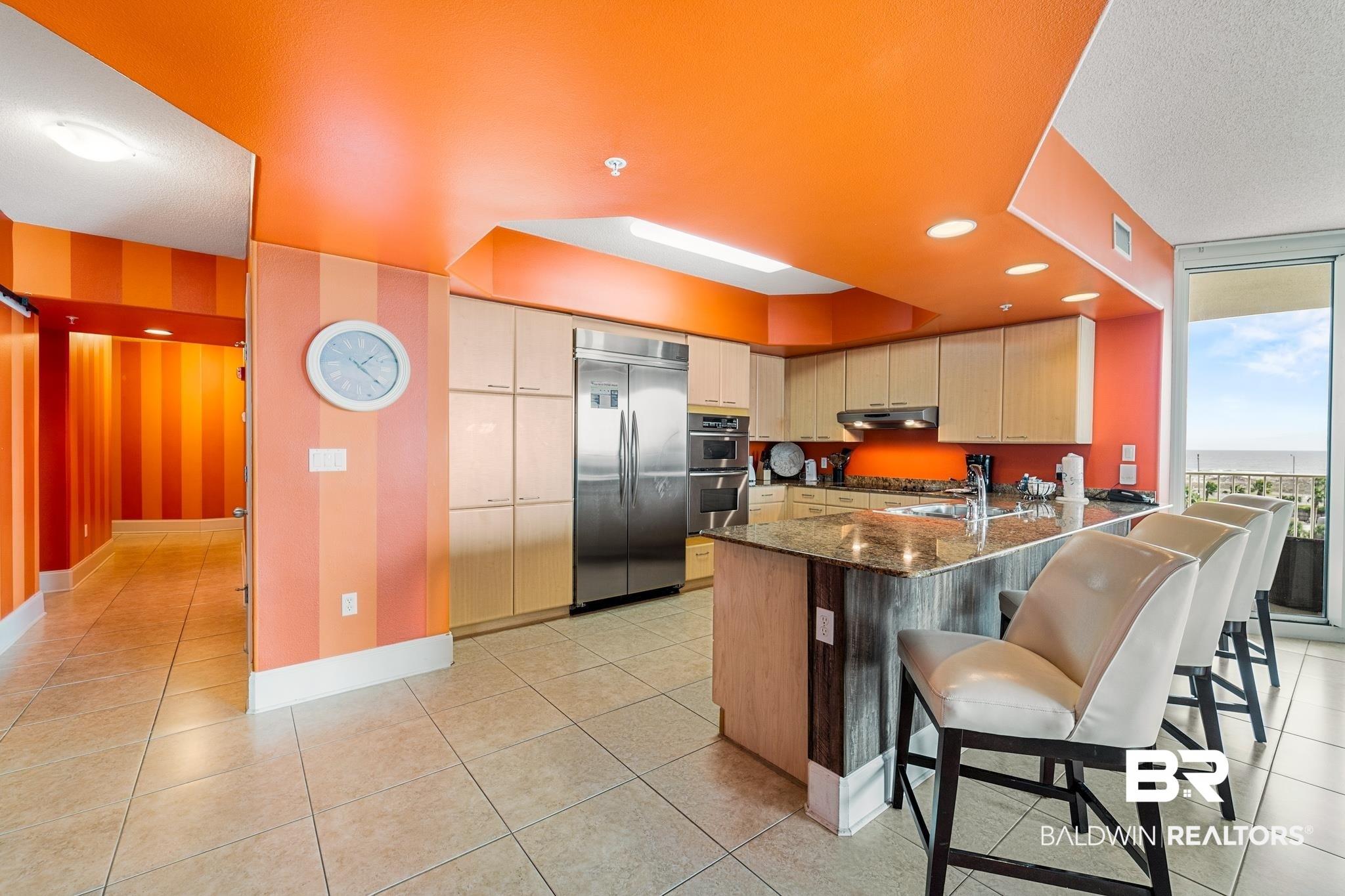 Image 4: Kitchen with dark stone counters, appliances with stainless steel finishes, a peninsula, a kitchen bar, and recessed lighting