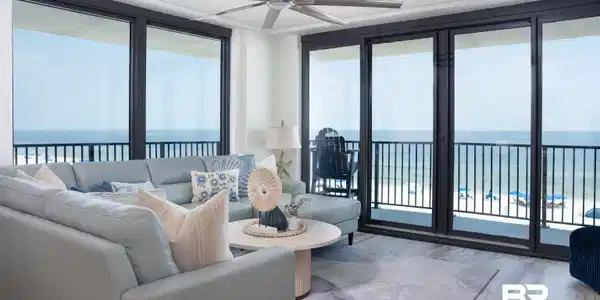 Image 2: Living space featuring full-height sliding glass doors opening to a balcony with metal railings and expansive ocean scenery