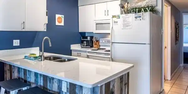 Image 3: Kitchen featuring white appliances, light tile patterned flooring, white cabinets, a peninsula, and a kitchen bar