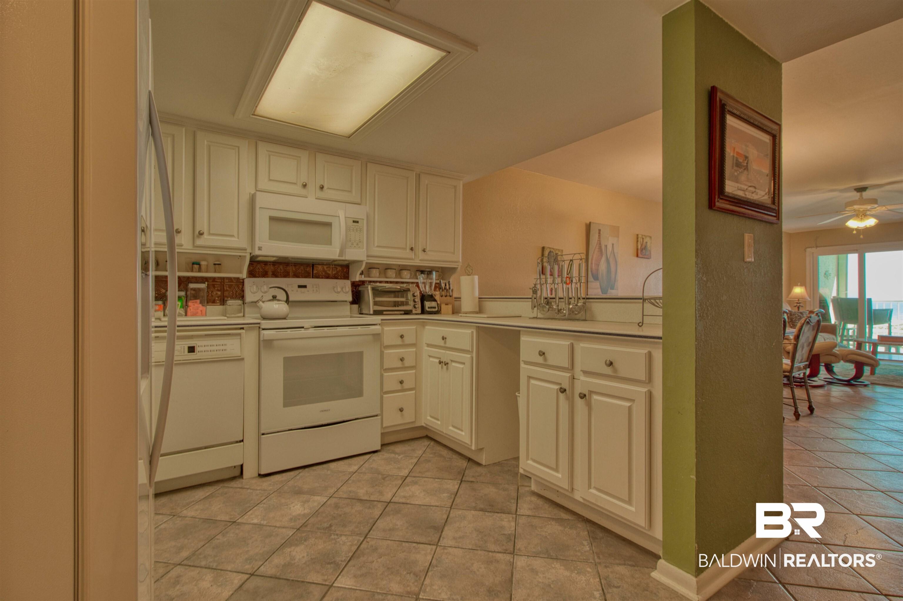 Image 3: Kitchen with light countertops, white appliances, ceiling fan, white cabinets, and light tile patterned flooring