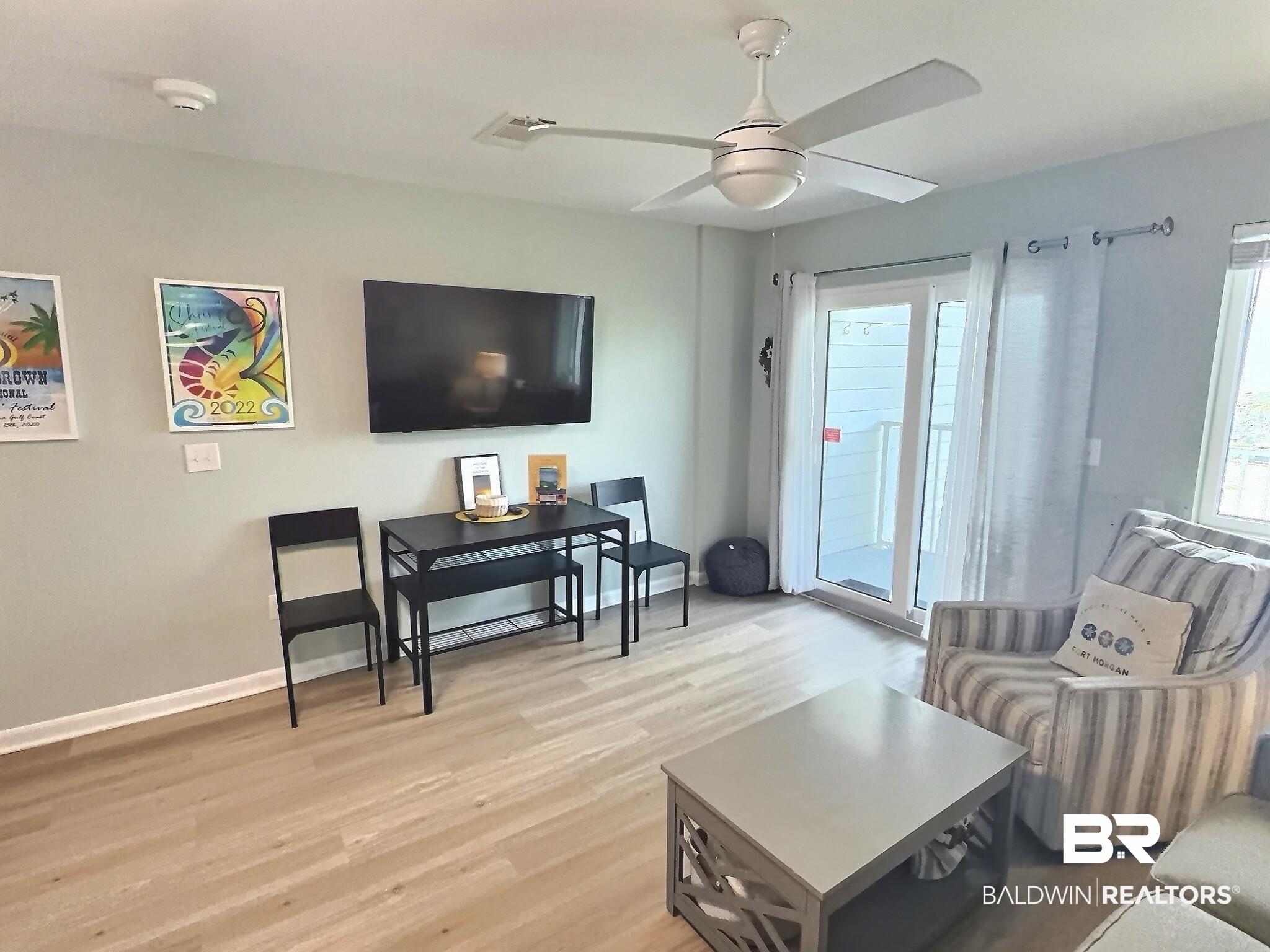 Image 4: Living area featuring light wood-finish flooring, a contemporary ceiling fan, and light-toned wall paint