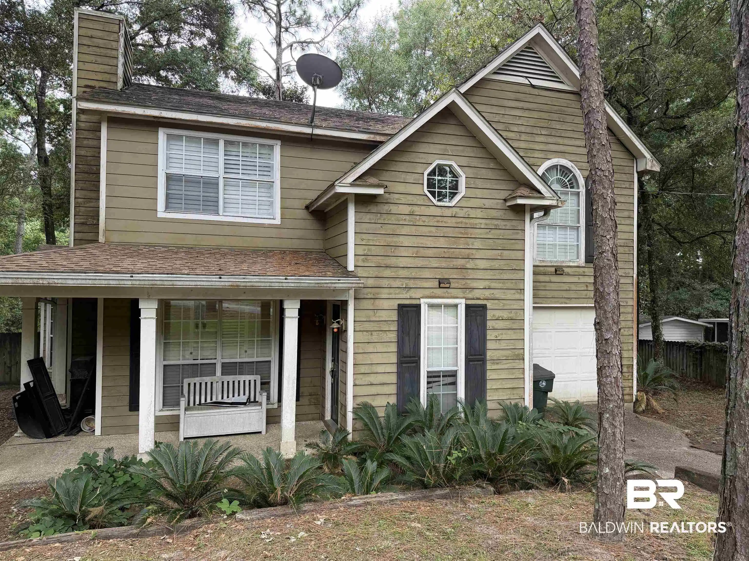 Image 1: Two-story residence featuring light brown siding and a covered front porch with white pillars