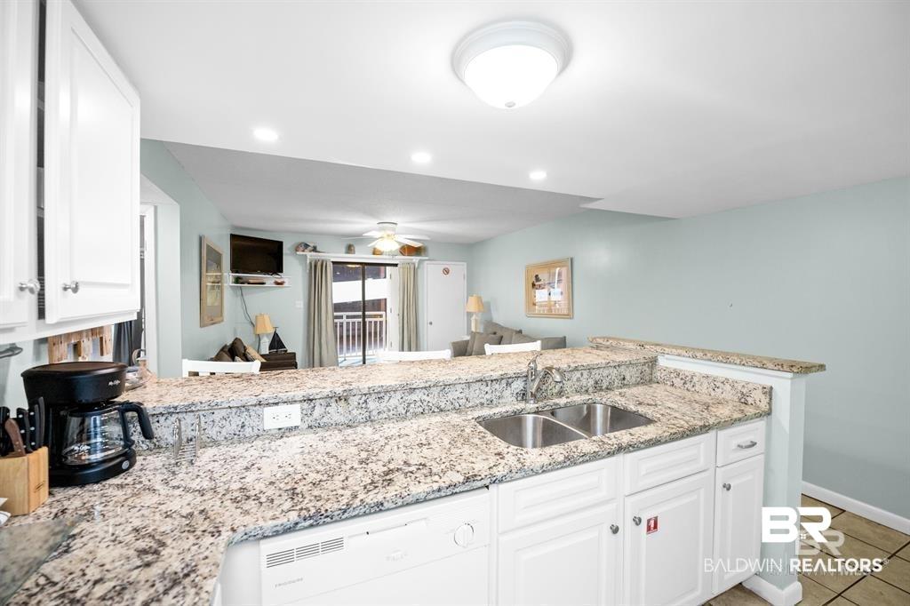 Image 3: Kitchen featuring white cabinetry, light stone counters, dishwasher, open floor plan, and recessed lighting