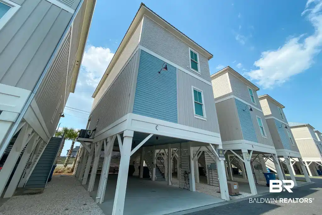 Image 1: Coastal-inspired exterior featuring siding with blue and tan accents, white trim, and multiple windows