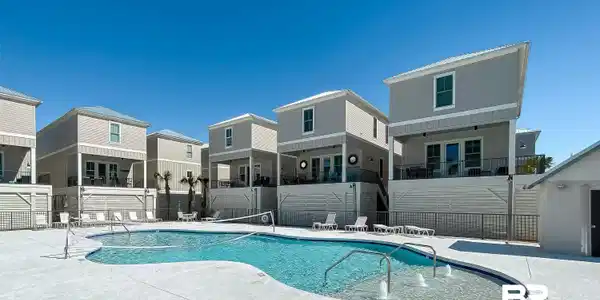 Image 4: Curved swimming pool with integrated fountains, surrounded by concrete decking and multiple lounge chairs
