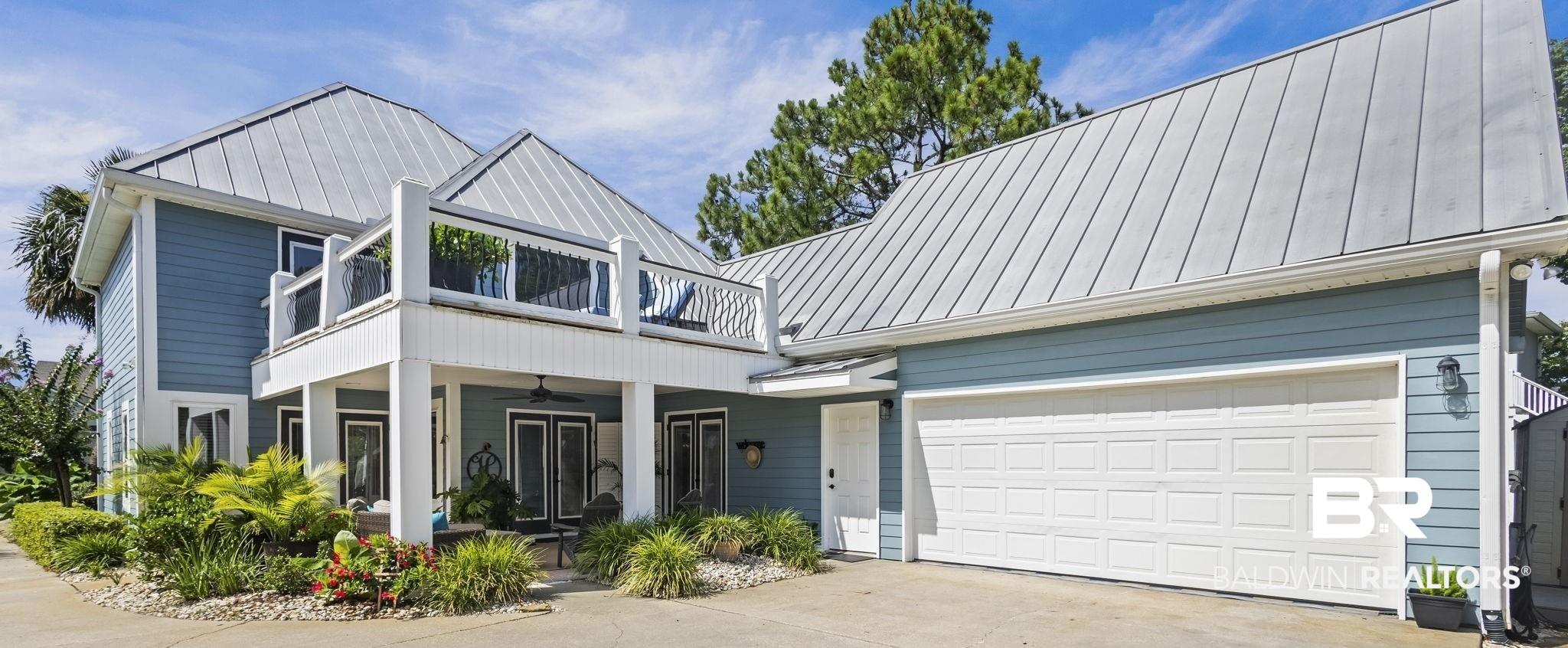 Image 3: View of front of property with a standing seam roof, a balcony, concrete driveway, and ceiling fan